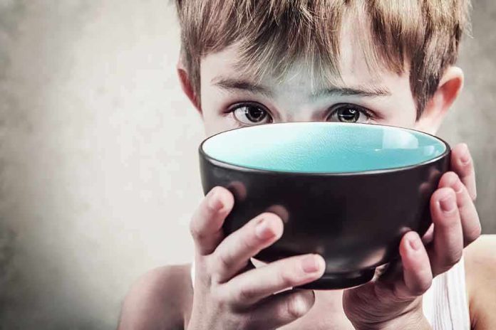 A child with a serious expression holding a bowl close to their face