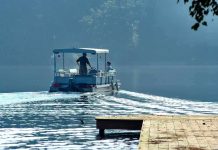 Two people on a boat navigating a misty lake
