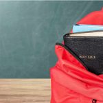 Red backpack with a Bible and books inside.