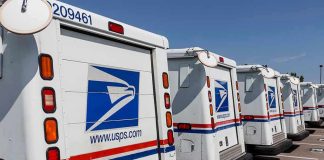 USPS COLLAPSES — Pension Payments HALTED Row of USPS mail trucks parked in lot.