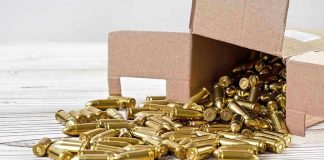 BRAZEN Daylight Siege — Bullets Fly Downtown Box of brass bullets spilled on wooden surface.