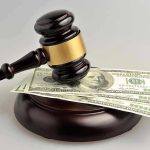 Gavel resting on hundred-dollar bills.