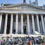 Courthouse facade with media crews setting up outside.
