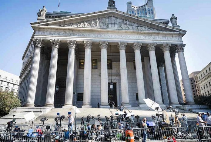 Courthouse facade with media crews setting up outside.