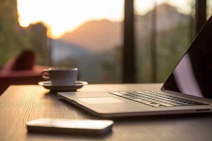 Laptop, coffee cup, and phone on wooden table.