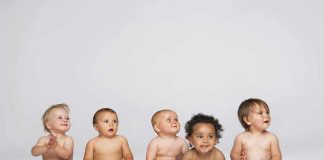 Five diverse babies sitting on a neutral background, displaying playful expressions