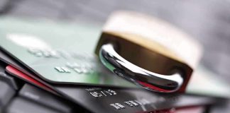 A padlock resting on top of multiple credit cards on a keyboard