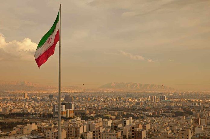 Iranian flag waving over a city skyline with mountains in the background