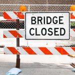 A Bridge Closed sign surrounded by safety barriers and fencing