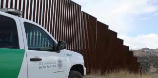 Trumps Top Chief QUITS – Mystery Deepens! Border protection vehicle near a large metal fence.