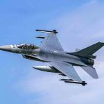 Jet fighter flying through clear blue sky.