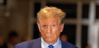 Man in blue suit and striped tie, serious expression.
