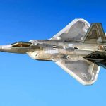 Fighter jet in flight against a clear blue sky.