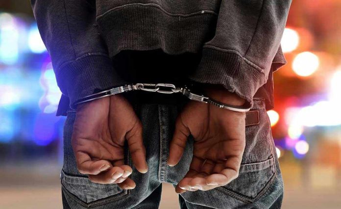 739687099 Person in handcuffs with colorful lights in background.