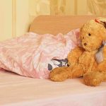 A cozy bedroom scene featuring a stuffed bunny and pink bedding