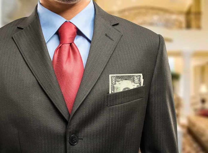 shutterstock_182553689 Man in a suit with a red tie and money peeking from his pocket