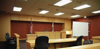 Immigration Judge Purge Leaves Asylum Cases In Chaos! Interior view of an empty courtroom with wooden furniture and American flags