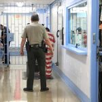 ICE Detentions SPIKE – Sets New Record! Corrections officers escort an inmate in a jail hallway