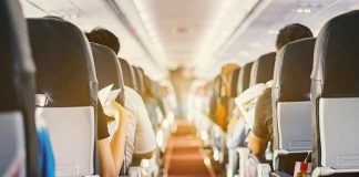Airplane cabin aisle with passengers seated