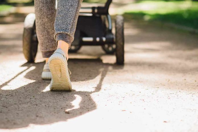 shutterstock_660811207 Person walking with a stroller on a sunlit path