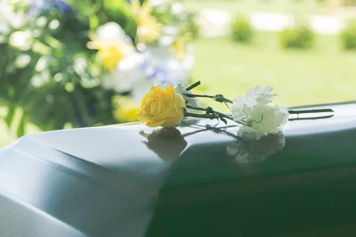 shutterstock_1014454810 Yellow rose and white carnation on a green casket