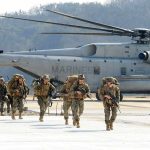 Embassy Alerts Spike — U.S Citizens URGED to Flee! Soldiers disembark and walk past a large military helicopter