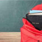 Dem Candidate Claims Jesus Wanted Socialism Red backpack with books on a classroom desk