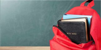 Red backpack with books on a classroom desk