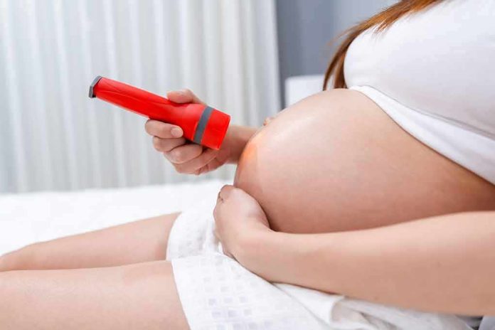 Pregnant woman shining flashlight on bare belly