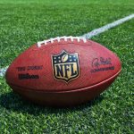 American football on a turf field near a white yard line