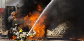 Gas Truck EXPLODES on Freeway into Fireball Firefighter spraying water on a vehicle engulfed in flames