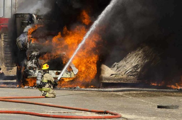 shutterstock_208835191 Firefighter spraying water on a vehicle engulfed in flames