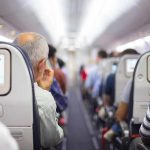 Laptop Ignites Midair — Cabin ERUPTS Airplane cabin aisle with passengers seated and seatback screens