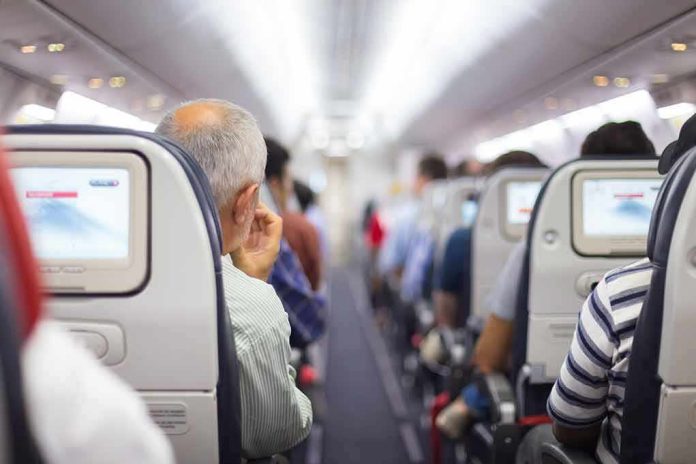 Airplane cabin aisle with passengers seated and seatback screens