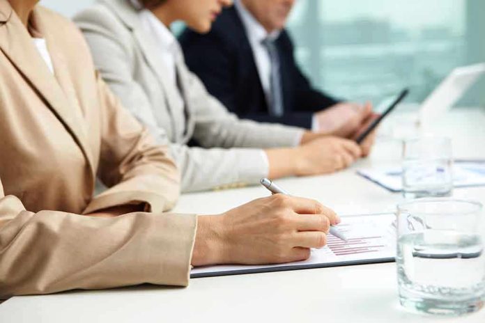Close-up of hands in business attire during a meeting, writing notes and reviewing documents