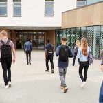 Students with backpacks walking toward a school entrance