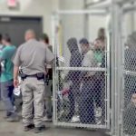 Senate Candidate Would Trade Five Americans for One Illegal Detention facility with people behind chain-link fence and officer nearby