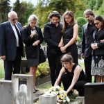 Mourners gathered at a graveside placing flowers