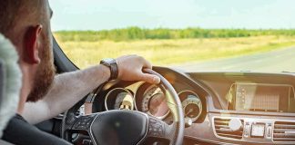 Driver's hands on steering wheel of car interior