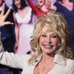 blonde woman waving at a red carpet event