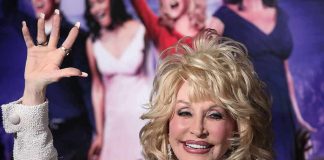 blonde woman waving at a red carpet event