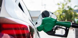 Green fuel nozzle pumping gas into a white car