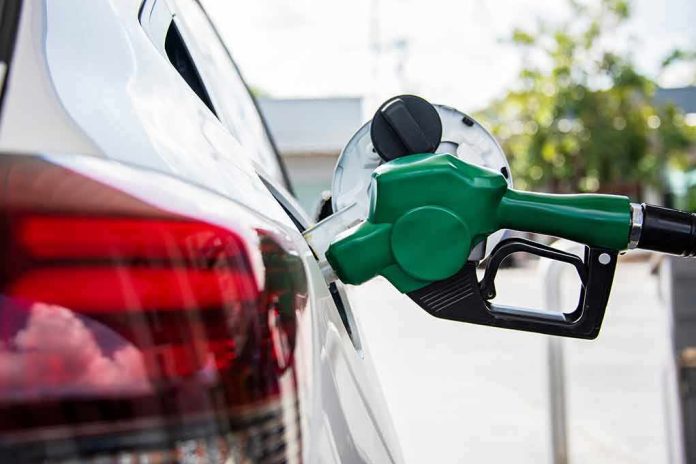 Green fuel nozzle pumping gas into a white car
