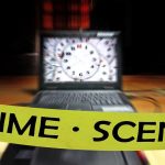 crime scene tape in front of a blurred laptop
