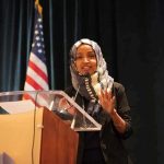 Woman in hijab speaking at a podium
