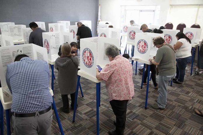 shutterstock_133686017-1 Voters fill out ballots at polling booths in a busy voting room