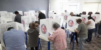 Voters fill out ballots at polling booths in a busy voting room