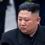 Kim Jong-Un looking to the side in a dark overcoat