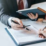 Hands signing a legal document at a desk