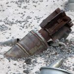 Mysterious Orbs Land On Beach Rusty metal machinery part embedded in gravel and sand